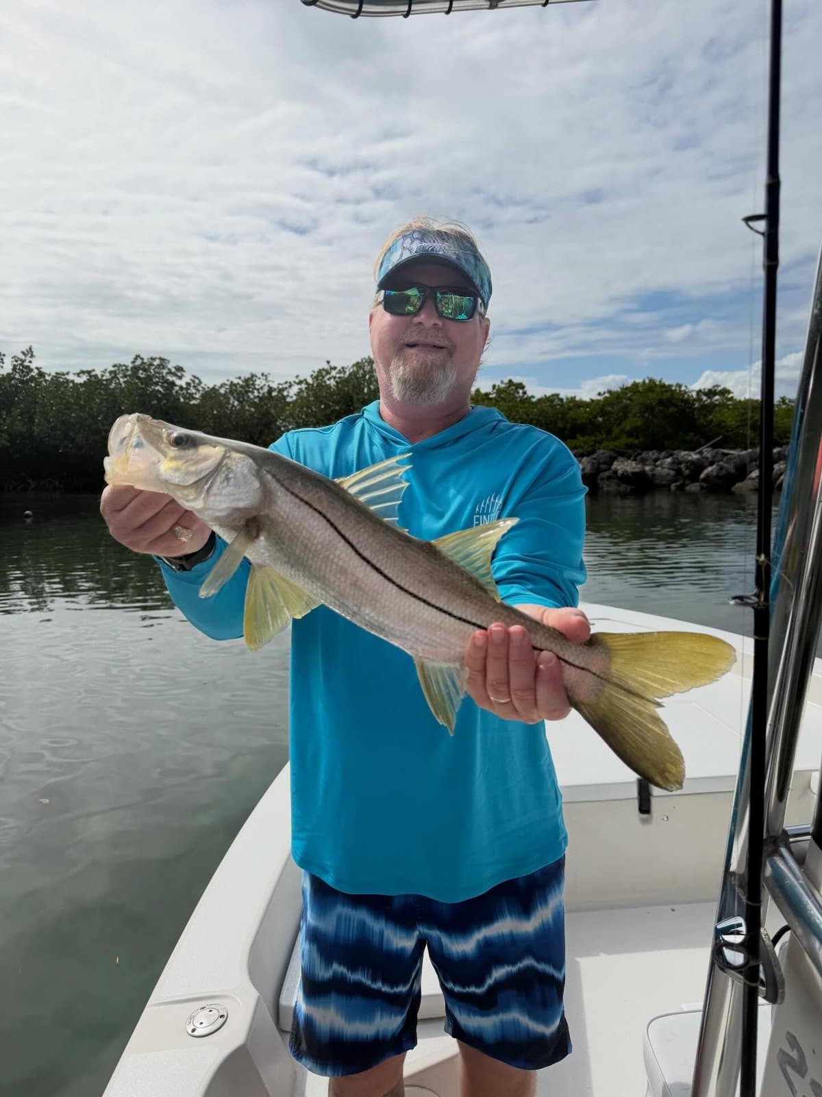 Angler holding a snook with the mangroves behind him