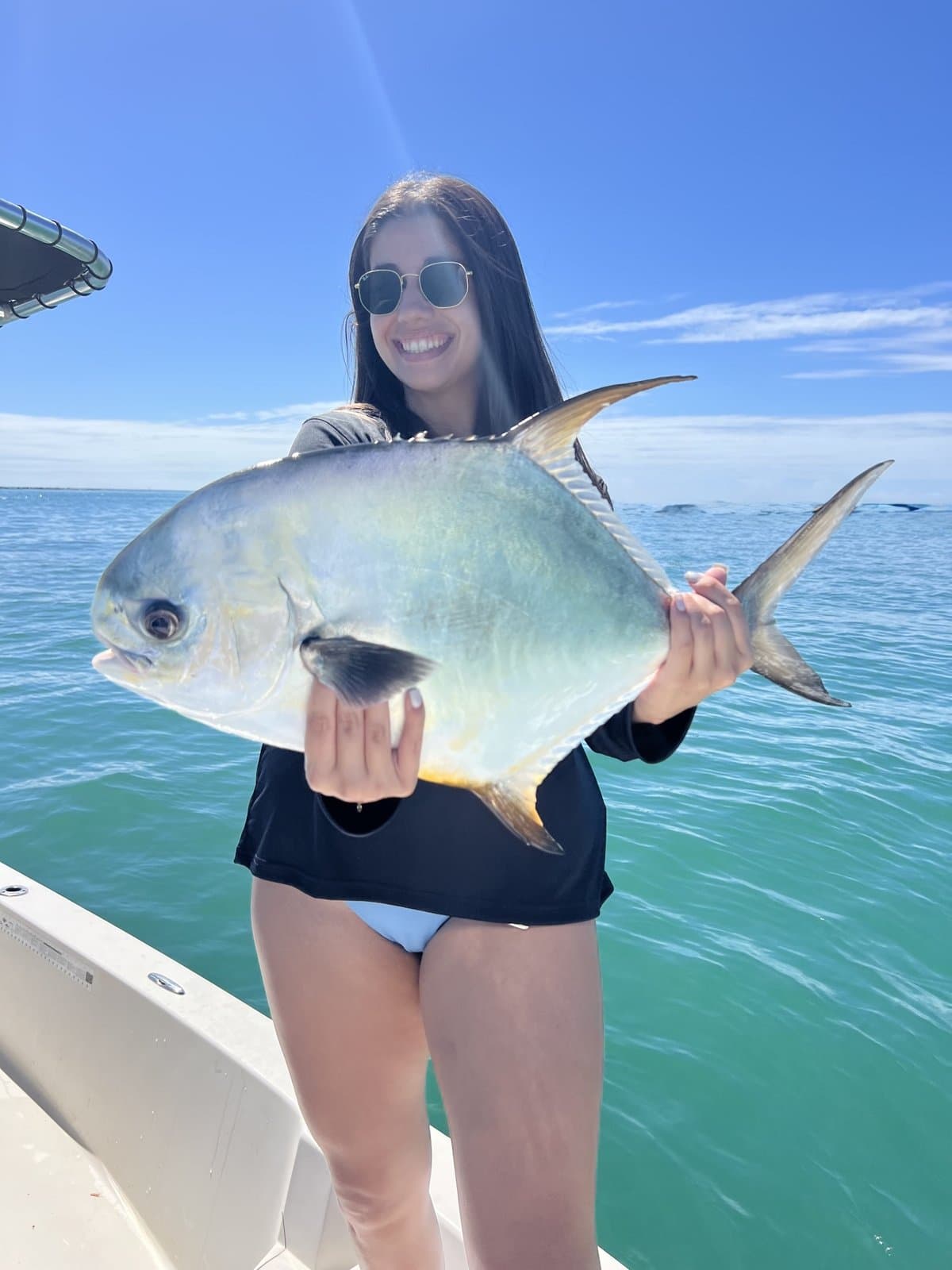 Smiling angler holding a big permit on the boat