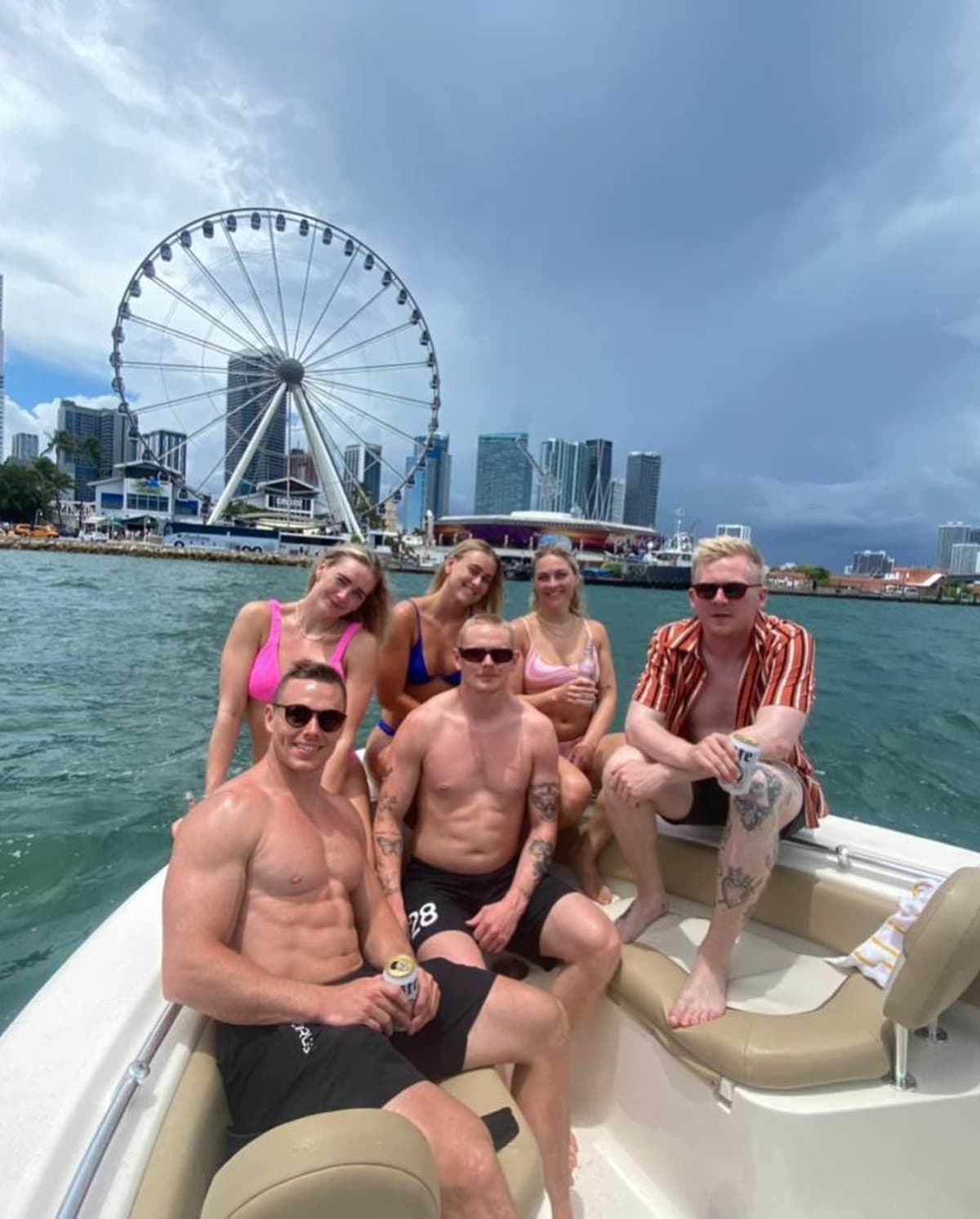 Group of friends aboard the boat with the Bayside Ferris wheel and Miami skyline behind them