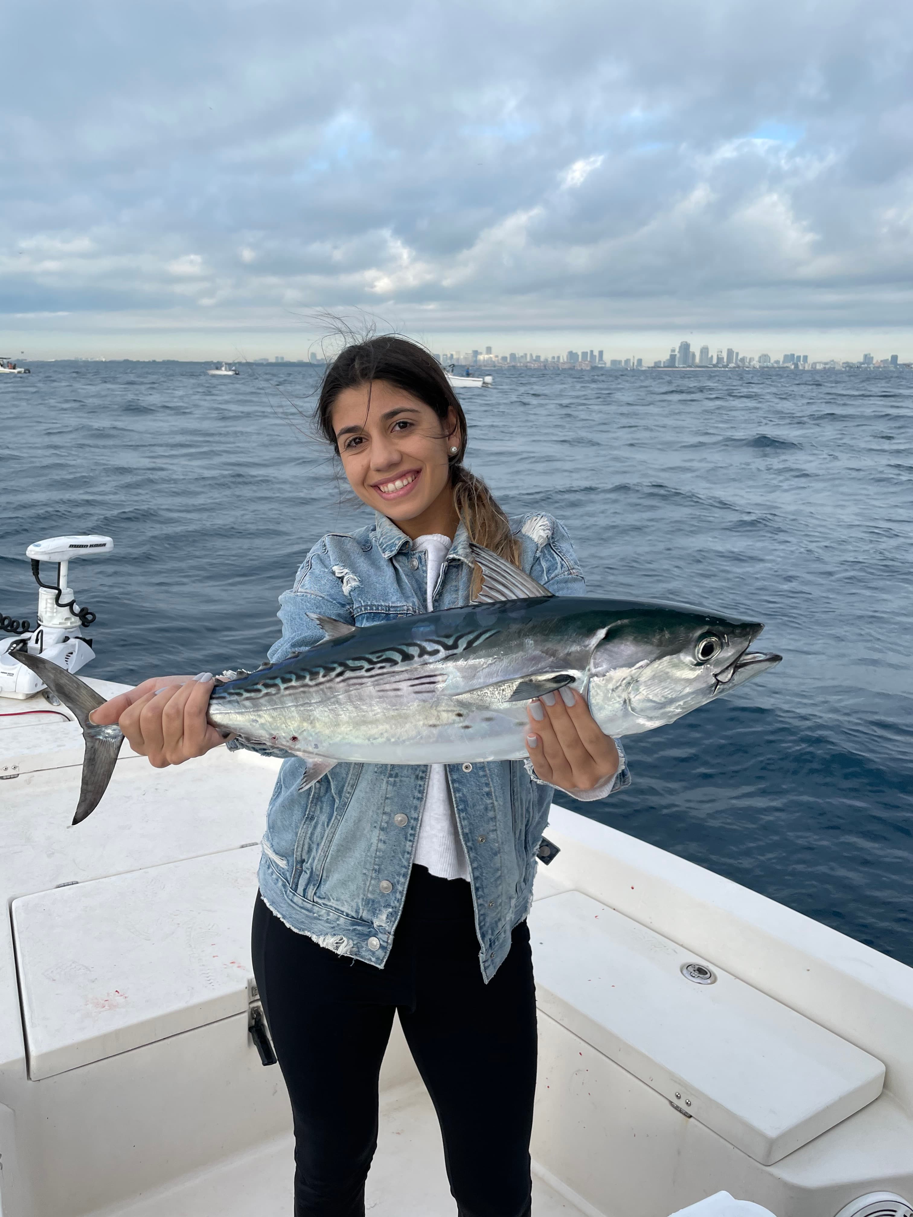 Angler holding a bonito with the city skyline behind