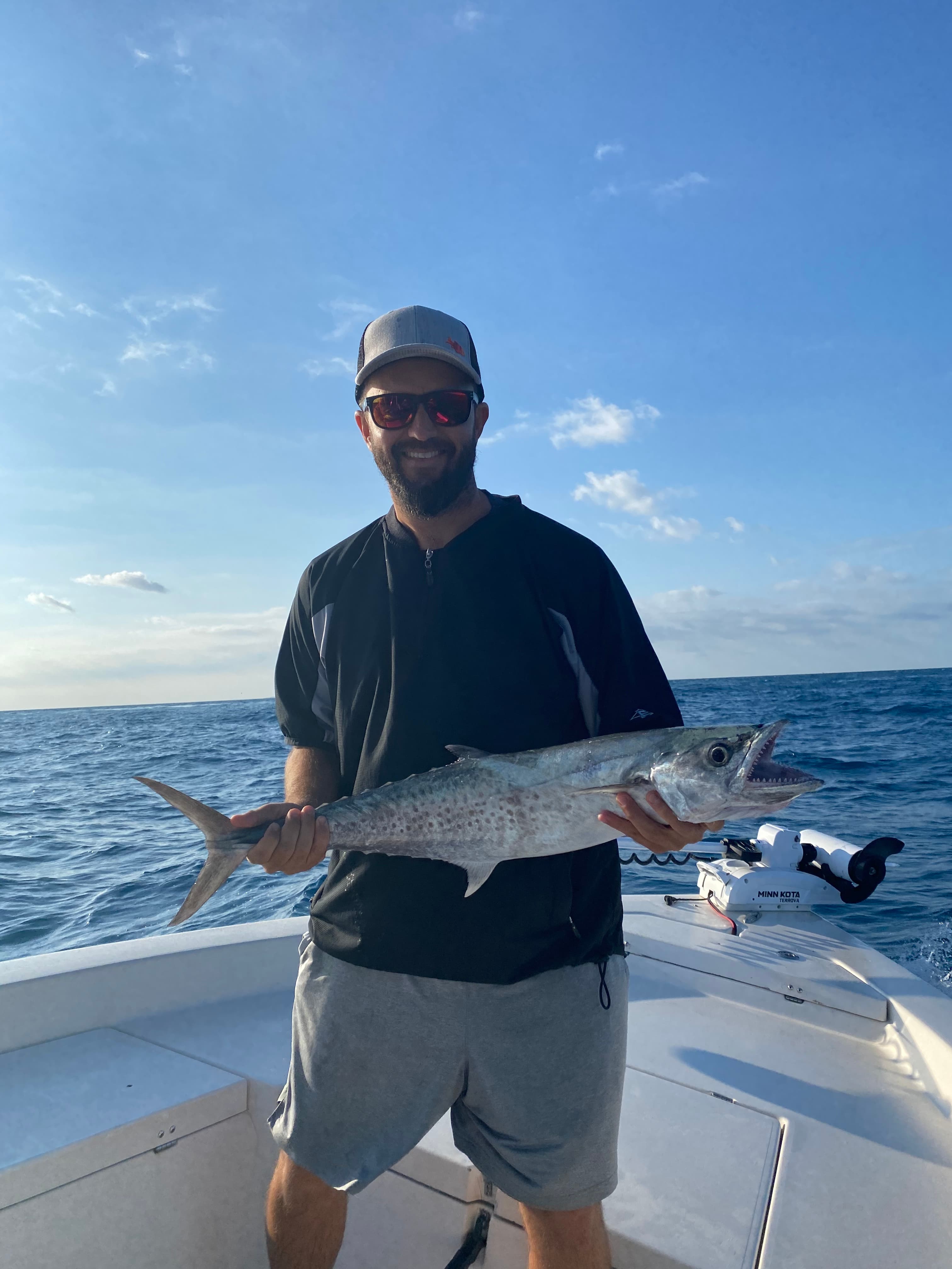 Smiling angler holding a kingfish on the boat