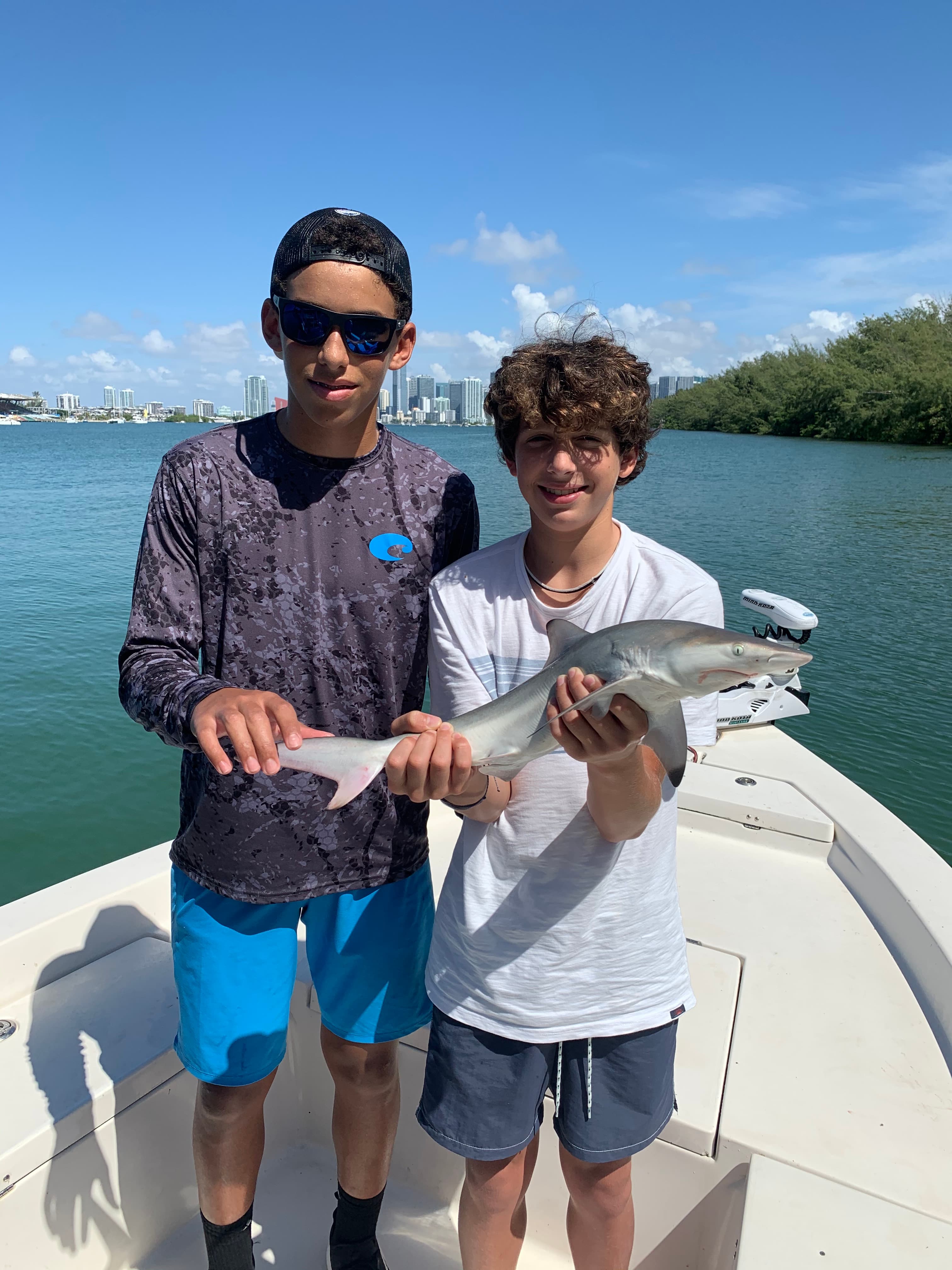 Two young anglers holding a small shark on the bow