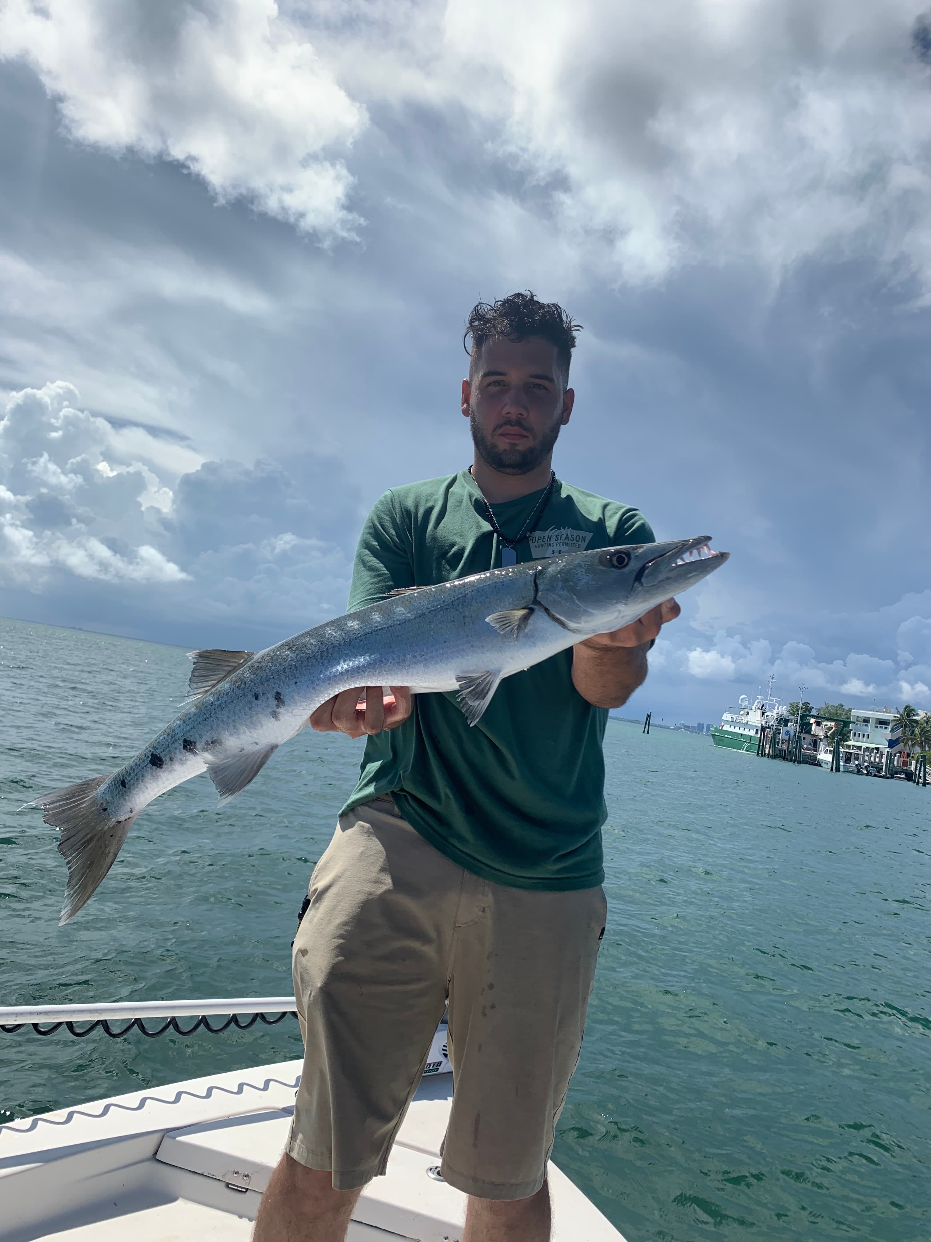 Angler holding a barracuda under a stormy sky