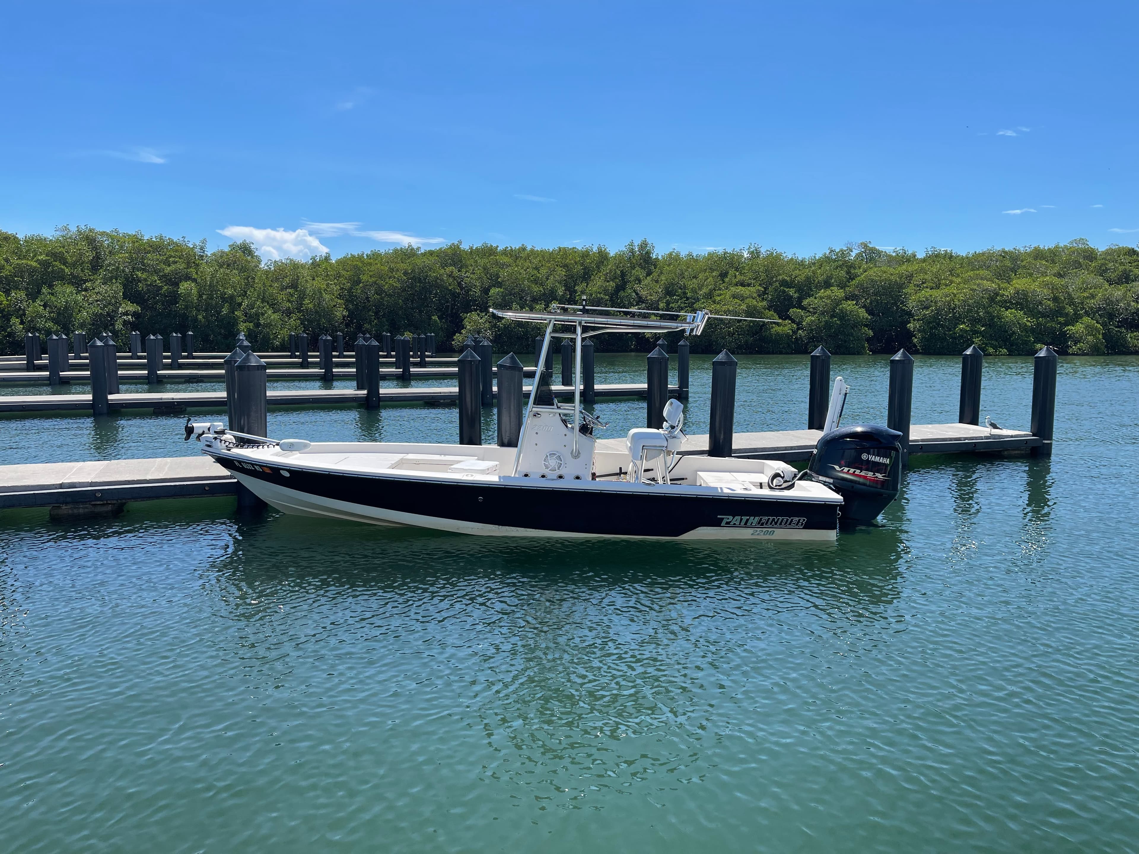 The black and white Pathfinder tied up at a marina with mangroves behind